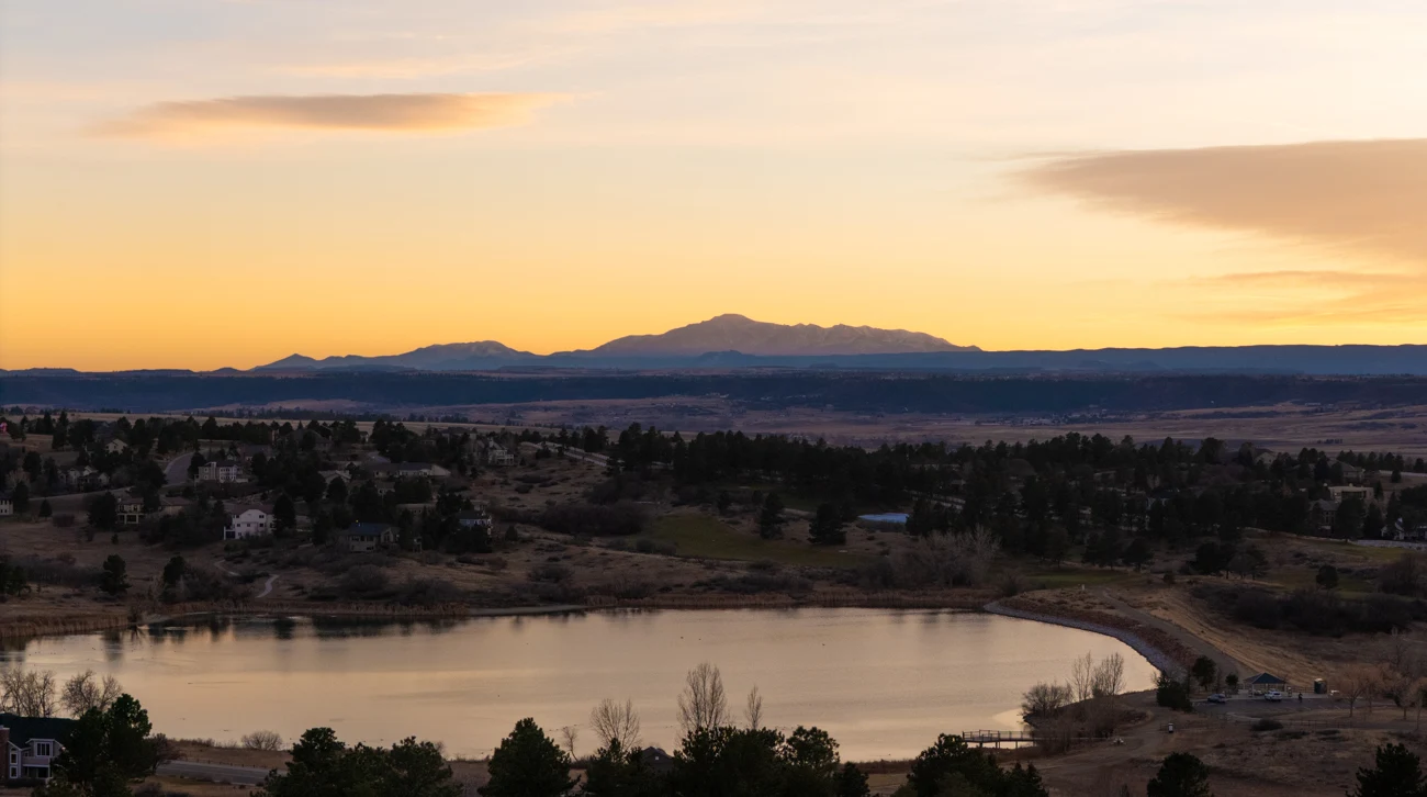 Evening light over the lake, neighborhood rooftops, and mountain horizon.